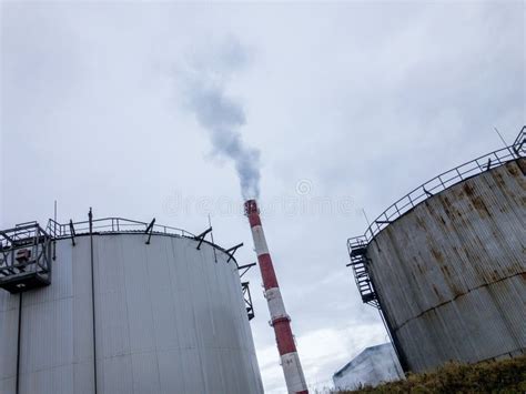 Industrial Oil Refinery Storage Tanks With Smokestack Pollution Stock