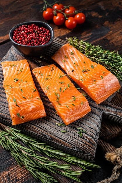 Filetes de salmón crudo sobre plancha de madera con tomillo y romero