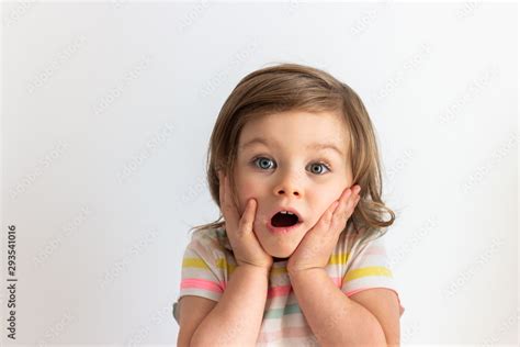 Surprised Shocked Toddler Child With Her Hands On Cheeks And Blue Eyes