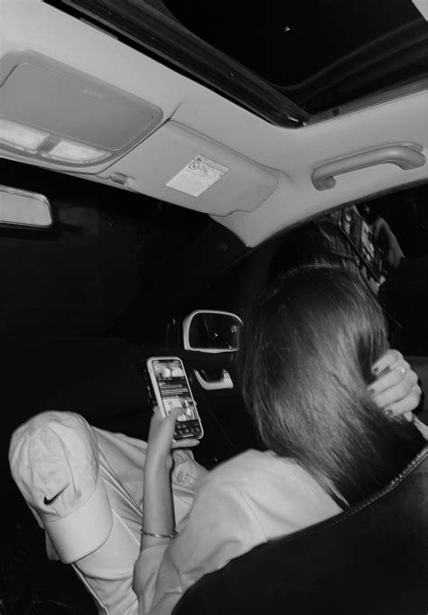 A Woman Sitting In The Back Seat Of A Car While Looking At Her Cell Phone