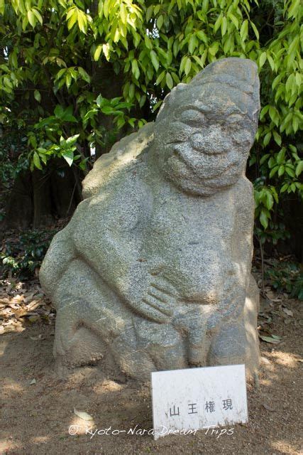 A Large Stone Statue Sitting In The Middle Of A Park With Trees And