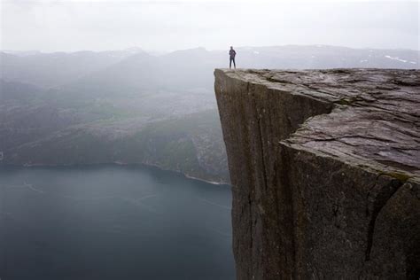 Caminante de niña feliz de pie en preikestolen y mirando las montañas