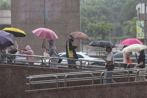 鋒面影響，中央氣象局7日針對北北基等16縣市發布大雨特報。圖為7日午後台北市中正區下起大雨，民眾撐傘外出。 圖：中央社 新聞