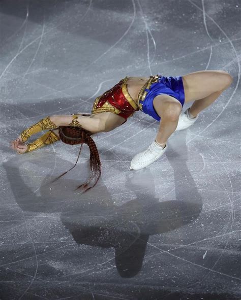 A Woman Is Performing On The Ice With Her Arms Extended And Legs Spread