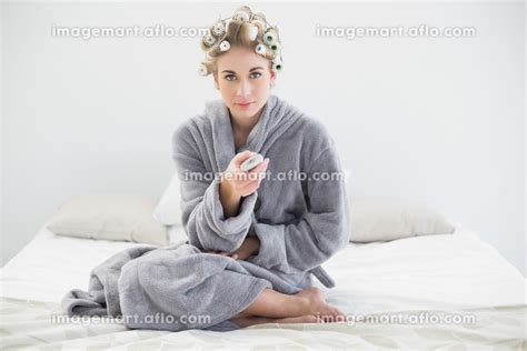 Pretty Relaxed Blonde Woman In Hair Curlers Using Remote Control In A