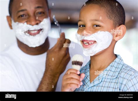 Father And Son With Shaving Foam On Their Faces The Father Is Shaving