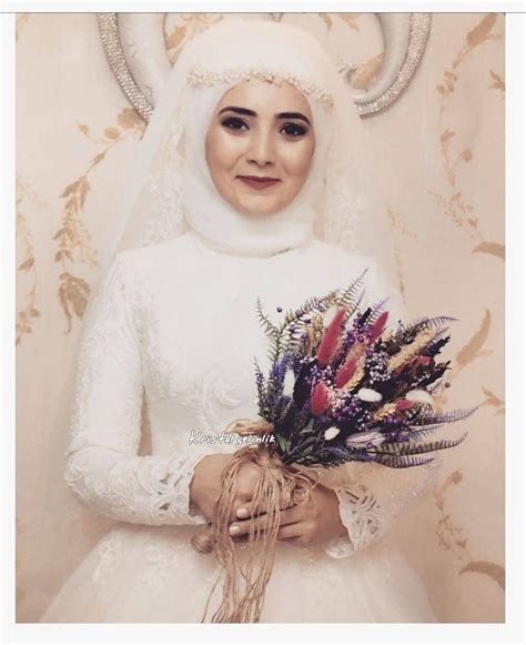 A Woman In A White Dress Holding A Bouquet Of Flowers And Wearing Horns