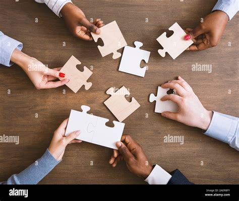 Group Of Business People Assembling Jigsaw Puzzle Together Stock Photo