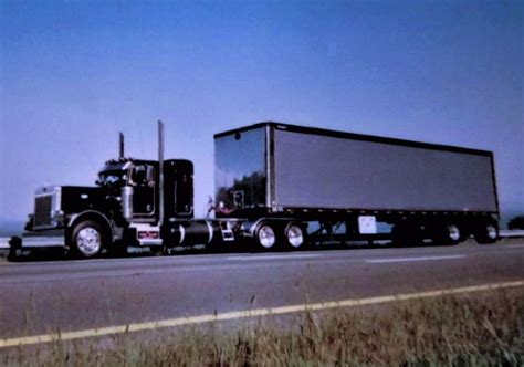 A Semi Truck Driving Down The Highway With Its Trailer Attached To It S