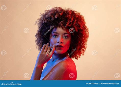 Biracial Woman Wearing Pink Eyeshadow And Lipstick Touching Chin In Red