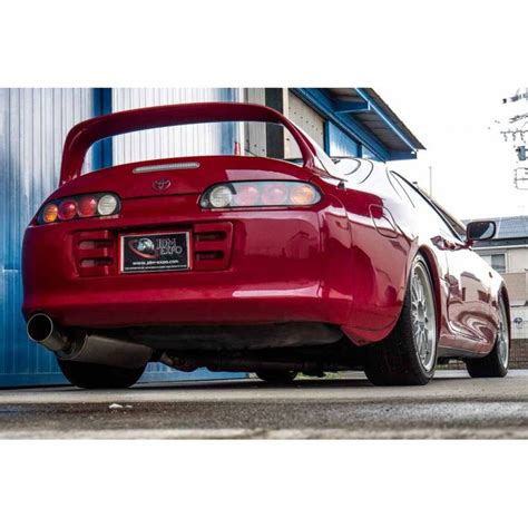 The Back End Of A Red Sports Car Parked In Front Of A Blue Garage Door