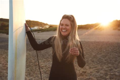 Woman Wearing Wetsuit Holding Surfboard Enjoying Surfing Staycation on Beach As Sun Sets Stock ...