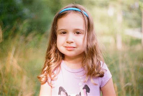 Portrait Of A Beautiful Young Girl Standing In A Field With Tall Grass