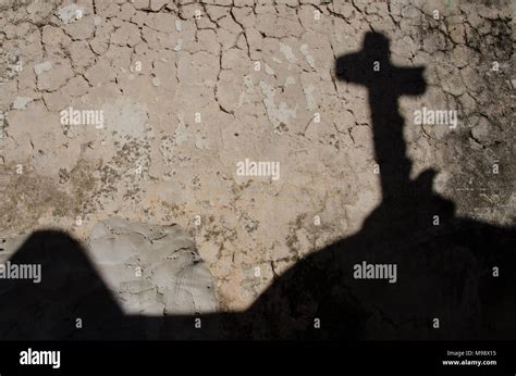 Shadow of religious cross on cracked clay wall. Religious symbolism ...