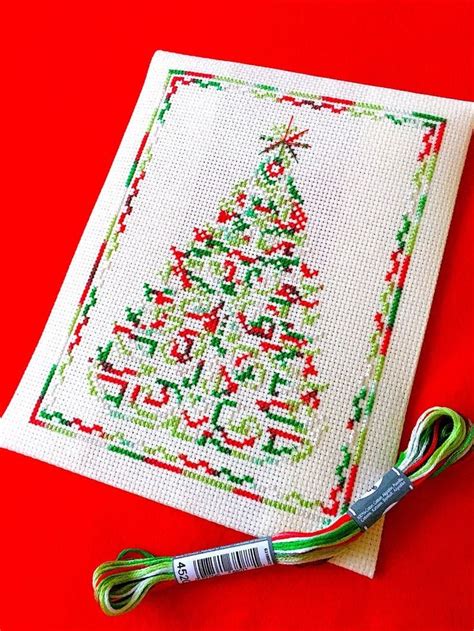 A Cross Stitch Christmas Tree On A Red Background With A Pair Of