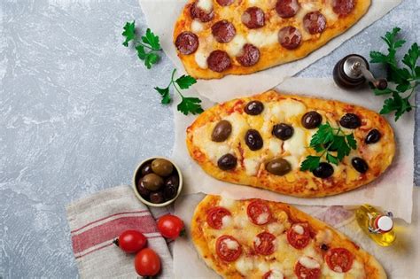 Trois différentes pizzas ovales aux olives tomates et salami sur un