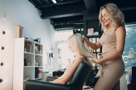 Premium Photo | Hairdresser female making hair extensions to young ...