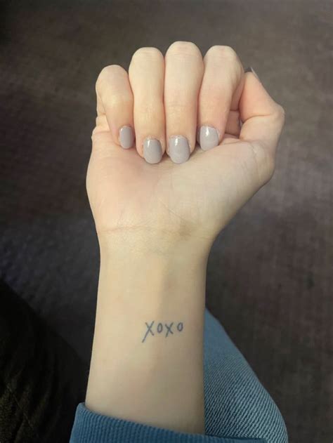 a woman's arm with a small tattoo on it and the word xoxo written