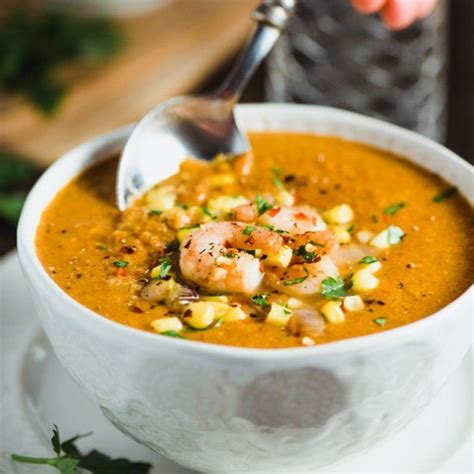 A Bowl Of Shrimp And Corn Soup With A Spoon In The Bowl Next To It