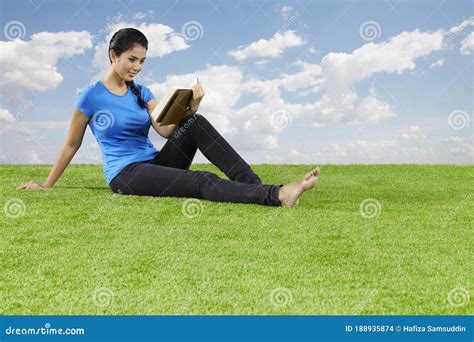 Young Woman Sitting On Grass Reading A Book Conceptual Image Stock