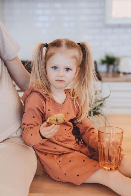 Shoot Vertical De Petite Fille Suédoise Blonde Avec Des Queues Assis Sur Une Table Tenant Un