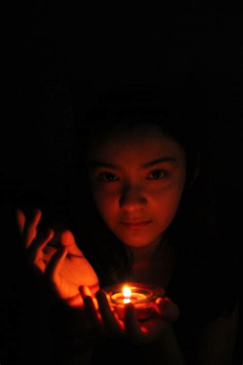 A Woman Holding A Lit Candle In Her Hands