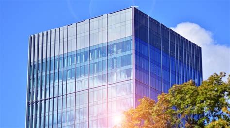 Un Edificio Con Una Fachada De Cristal Azul Y El Sol Brillando En Las