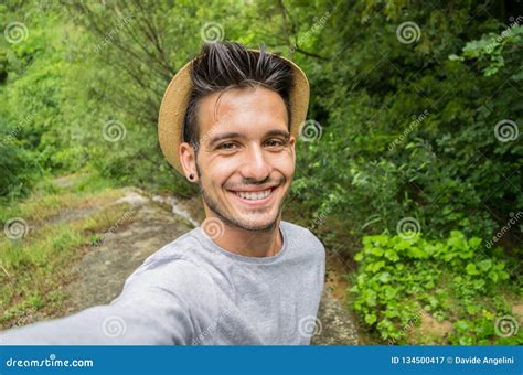 Handsome Man Smiling On The Camera Taking A Selfie In A Forest Stock