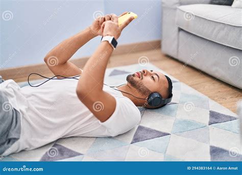 African American Man Listening To Music Lying On Floor At Home Stock