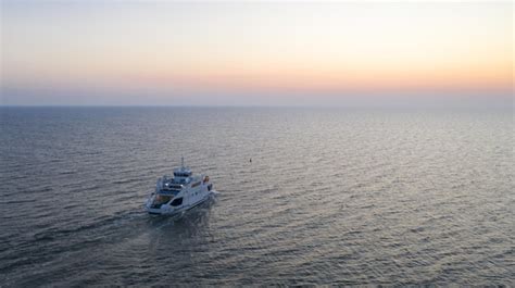 Foto aérea de um iate navegando em um mar azul durante o pôr do sol