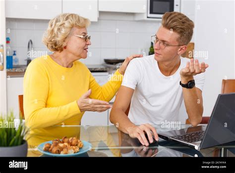 Happy Mature Woman Proud Of Her Adult Son Working With Laptop At Kitchen Stock Photo Alamy