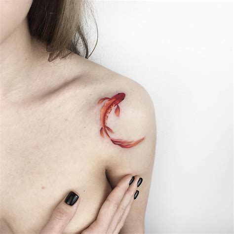 A Woman S Shoulder With A Red Fish Tattoo On Her Left Shoulder And