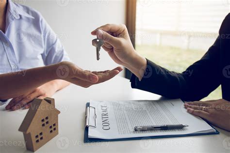 Hand Of Real Estate Agent Passes The Key To New Homeowners In Office With Buyer House Concept