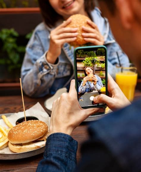 Hombre Tomando Foto De Mujer Comiendo Hamburguesa Foto Premium