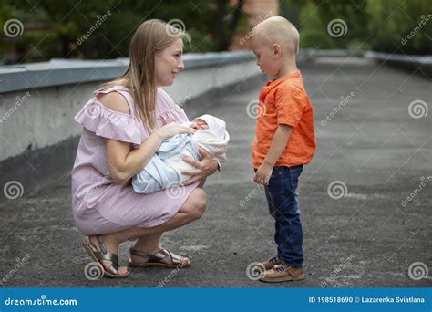 Mutter Zeigt Ihrem Sohn Eine Neugeborene Schwester Stockfoto Bild