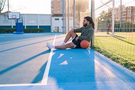 Hombre Afrolatino Con Una Pelota Sentada En Una Cancha De Baloncesto Al