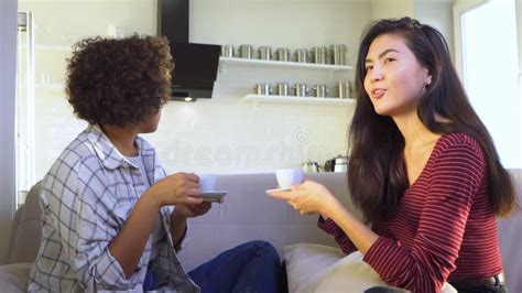 Two Girlfriends Gossiping While Sitting On The Couch Stock Video