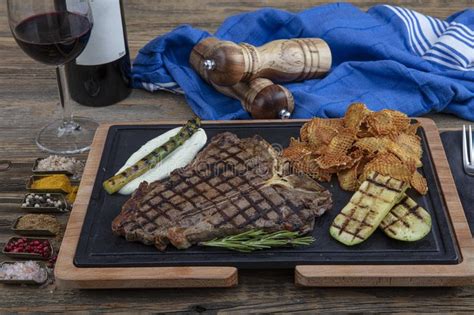 Barbecued T Bone Steak Seasoned With Fresh Herbs And Marinade Served With A Cutting Board In A