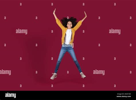 Happy African American Kid Girl Jumping On Burgundy Background Stock