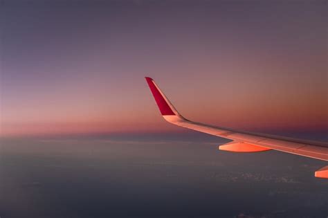 Asa de um avião no céu durante o pôr do sol Foto Premium