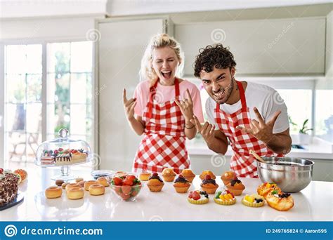 Couple Of Wife And Husband Cooking Pastries At The Kitchen Shouting With Crazy Expression Doing