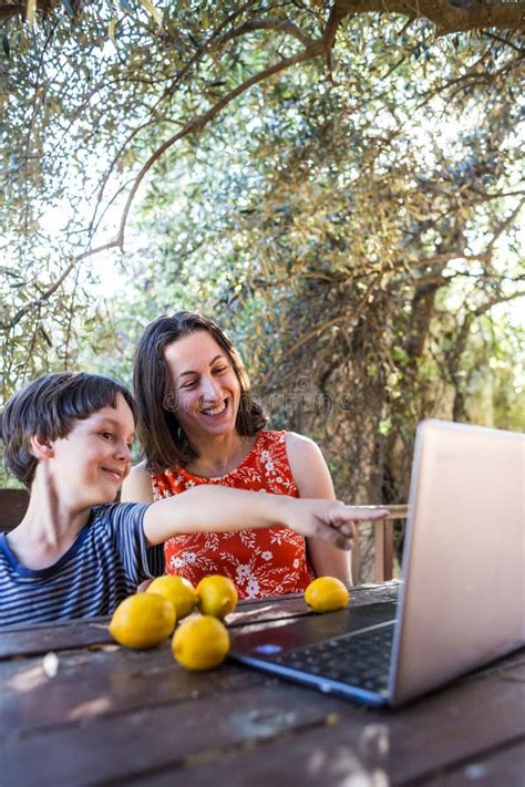 Mama Z Dzieckiem Siedzi Na Tarasie Drewnianego Domu I Patrzy Na Laptopa