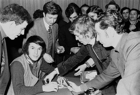 A Group Of People Sitting Around A Table Playing Cards