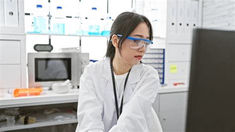 Young Asian Woman Scientist Working In A Modern Laboratory Wearing Lab Coat And Safety Glasses