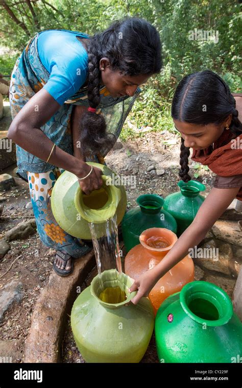 Rural Indian Village Woman And Girl Filling Water Pots From A Communal