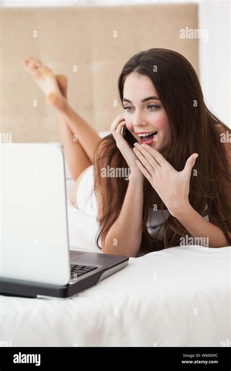 Pretty Brunette On The Phone In Bed Using Laptop At Home In The Bedroom Stock Photo Alamy