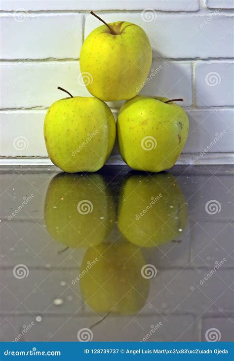 Three Golden Apples And Reflection On The Countertop Stock Image