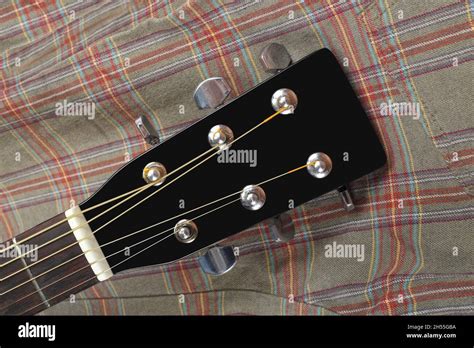 Musical Instrument Headstock Peghead Black Acoustic Guitar On A Cloth Fiber Plaid Background