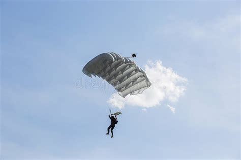 Parachutist With Parachute Is Flying In The Blue Sky Stock Photo