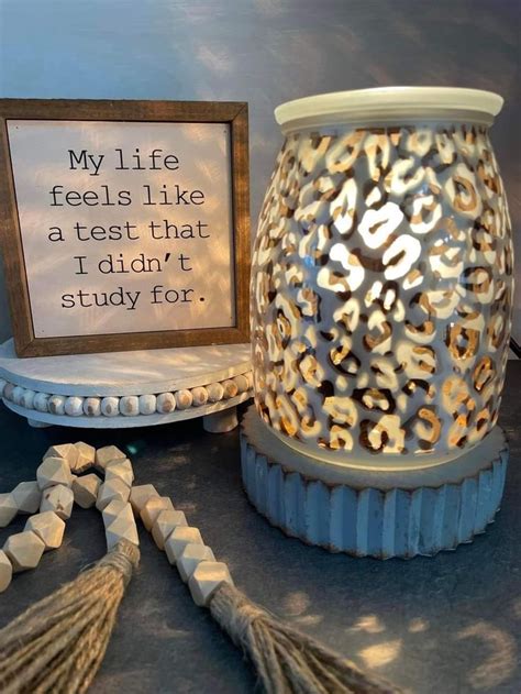 A White Vase Sitting On Top Of A Table Next To A Framed Sign And Tassels